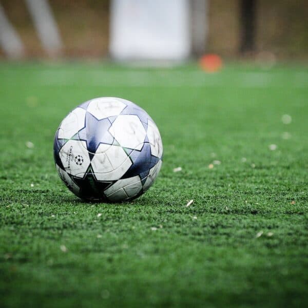 white and blue soccer ball on green grass field during daytime